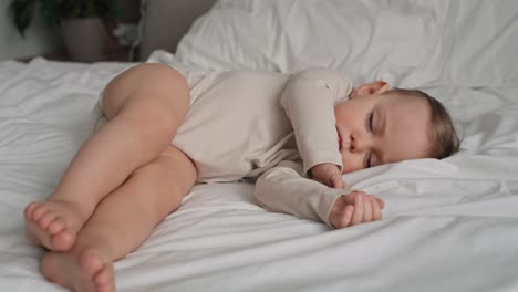 un video de una niña caucásica durmiendo en la cama de su casa.