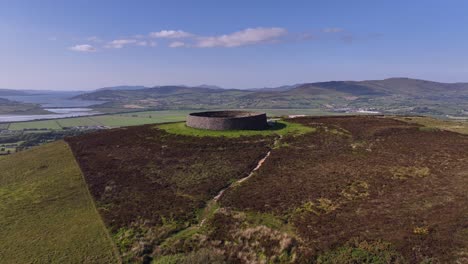 grianan of aileach, county donegal, ireland, june 2023. drone aerial flyover pushes forward over the stone ringfort at inishowen revealing the view north to inch wildfowl reserve and lough swilly.