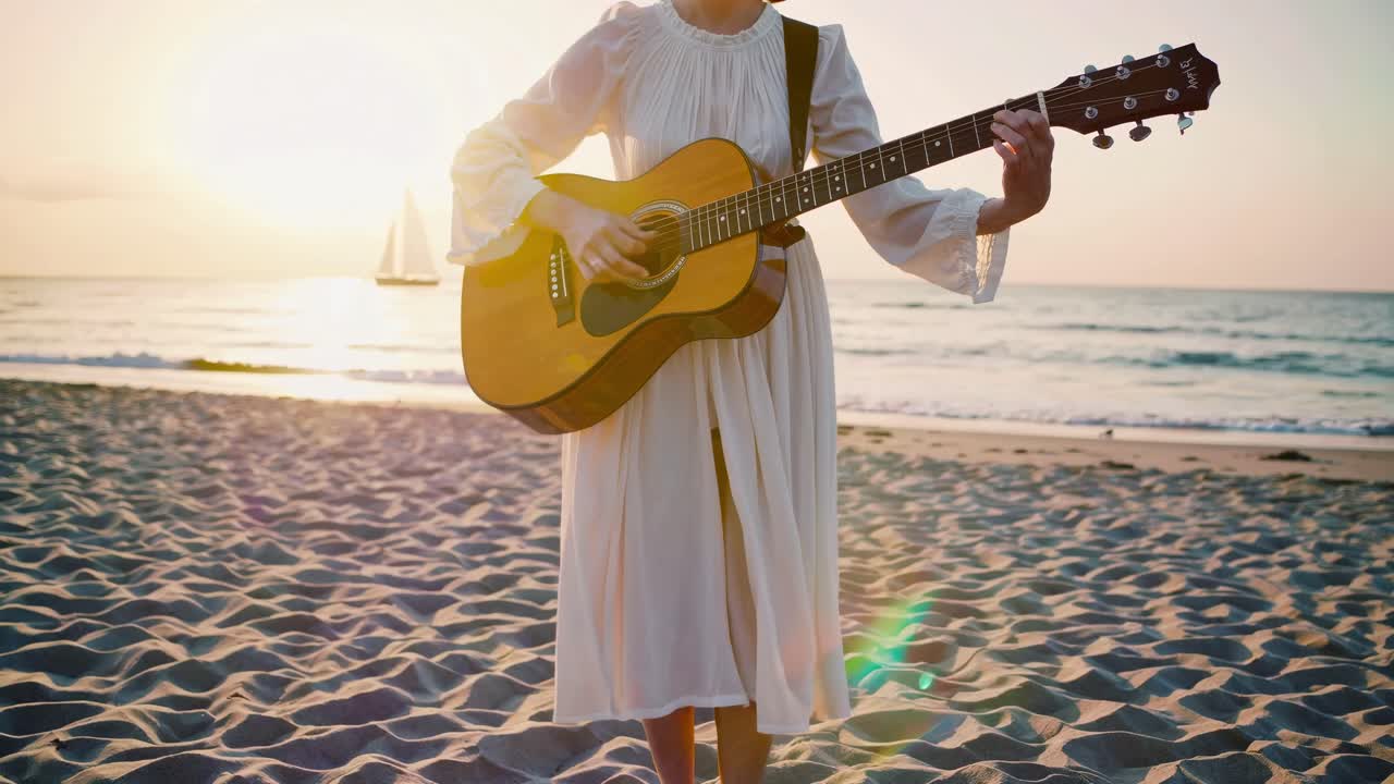 A serene video scene of a woman playing guitar on a beach at sunset