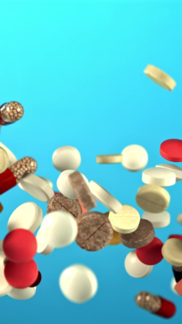 Colorful Pills and Capsules Rising in Slow Motion on Blue Background