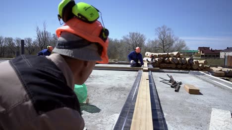 house construction workers laying wooden beams on foundation