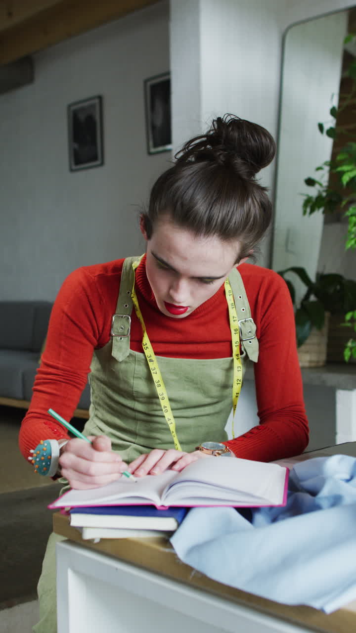 video vertical de una mujer transgénero caucásica no binaria trabajando en casa, tomando notas