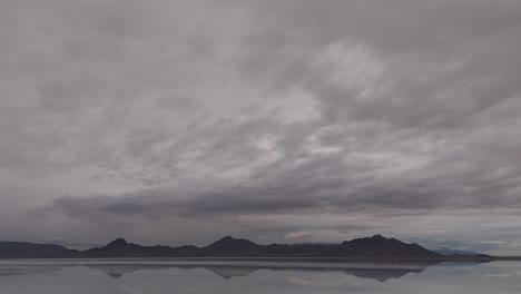 drone tilt down to low reverse flight over bonneville salt flats with water reflecting the sky and clouds