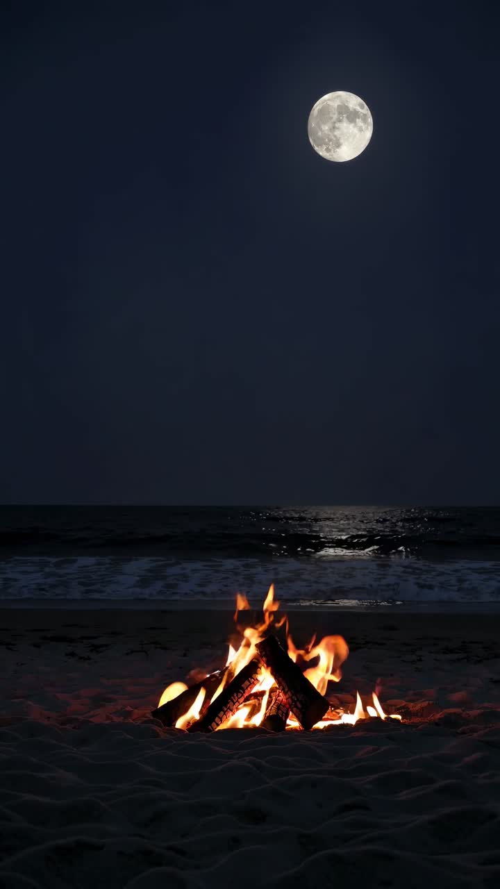 Uma cena serena de praia com uma fogueira sob a lua cheia. Foto tirada de um ângulo baixo