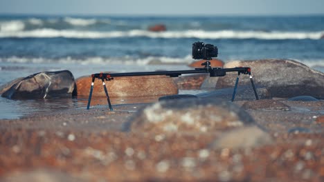 a camera on the slider filming a timelapse set up on the rocky beach