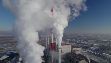 aerial close orbit over the coal-fired heating power station with thick white smoke coming from the chimney, environmental pollution concept