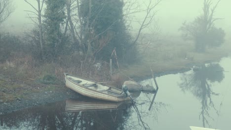 Fiberglass-rowboat-with-outboard-engine-beached-on-river-shoreline