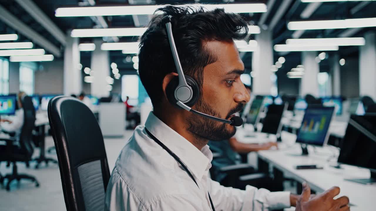 Video of a call center employee wearing a headset, focused on a computer screen