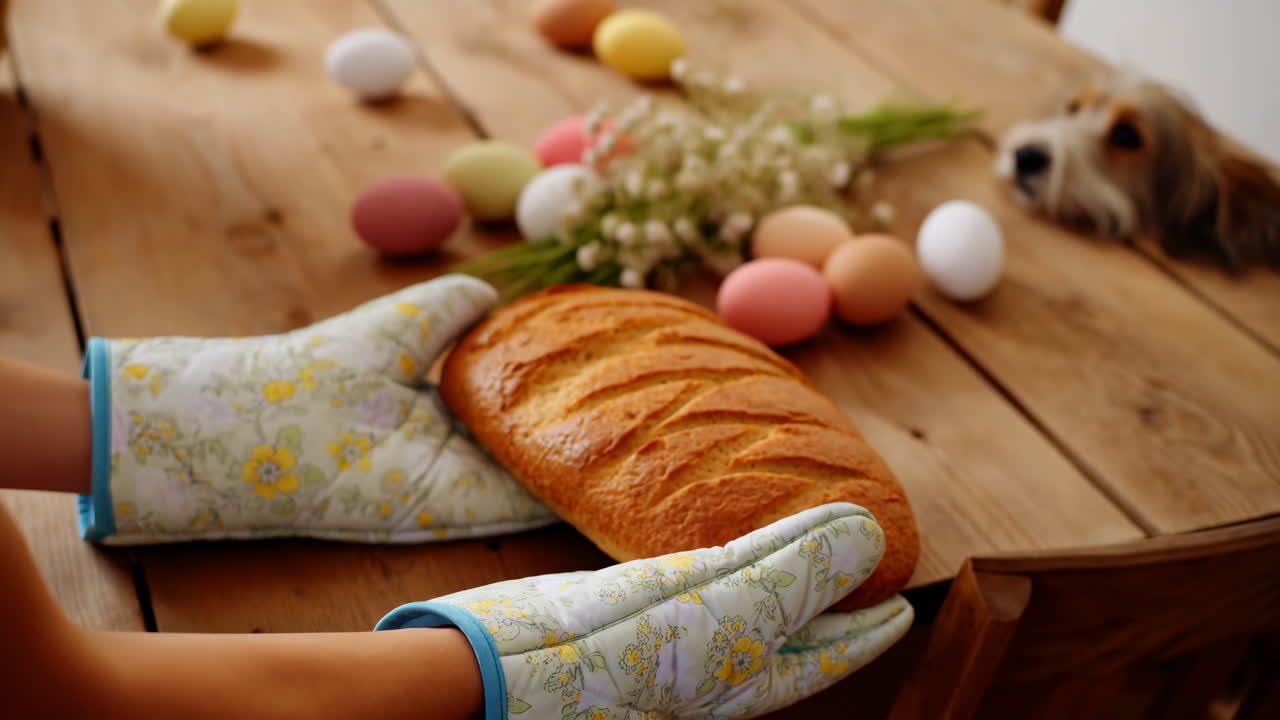 Hands in Oven Mitts Holding Freshly Baked Bread on a Wooden Table