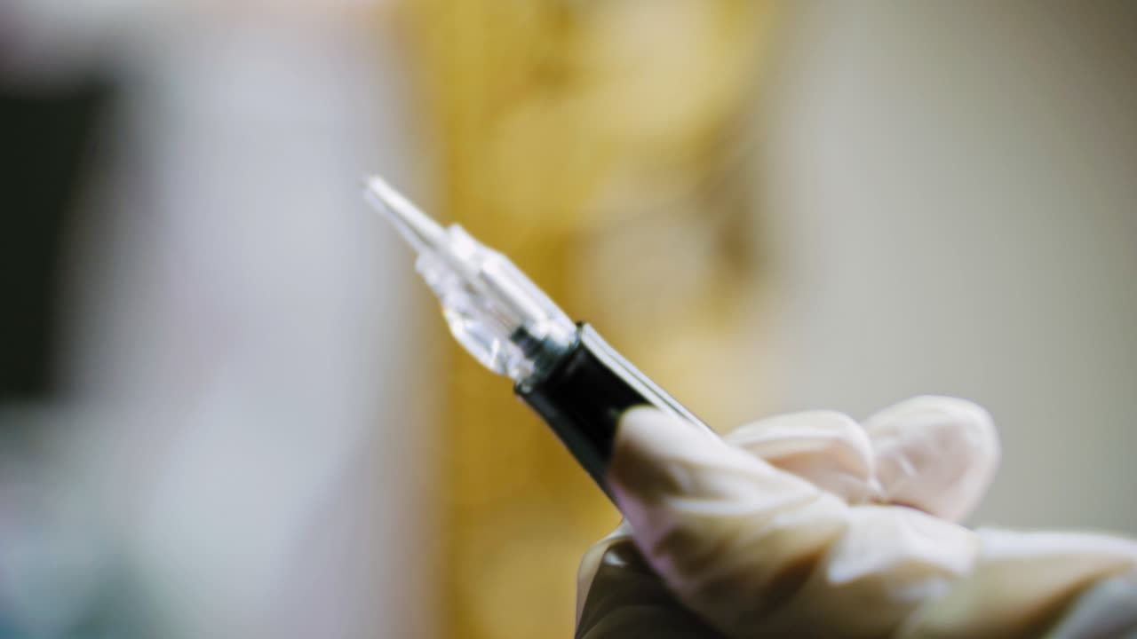 A beautician holds in her hand a pen for permanent makeup and checks it before the procedure. Close-up. Blurred background. Beauty industry.