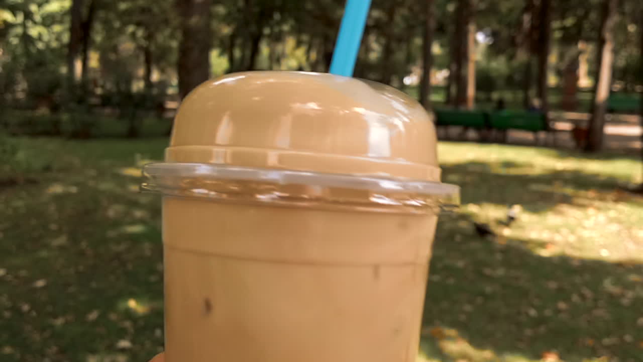 Primo piano di un bicchiere di latte macchiato freddo in un parco
