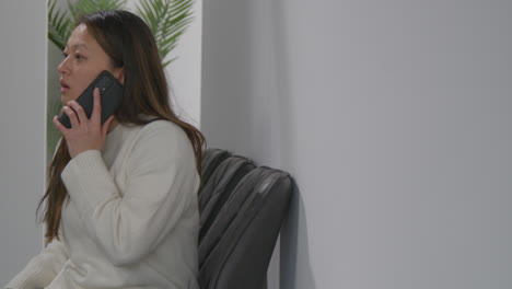 Anxious-Or-Stressed-Woman-Taking-Call-On-Mobile-Phone-At-Work-In-Office-Building-1