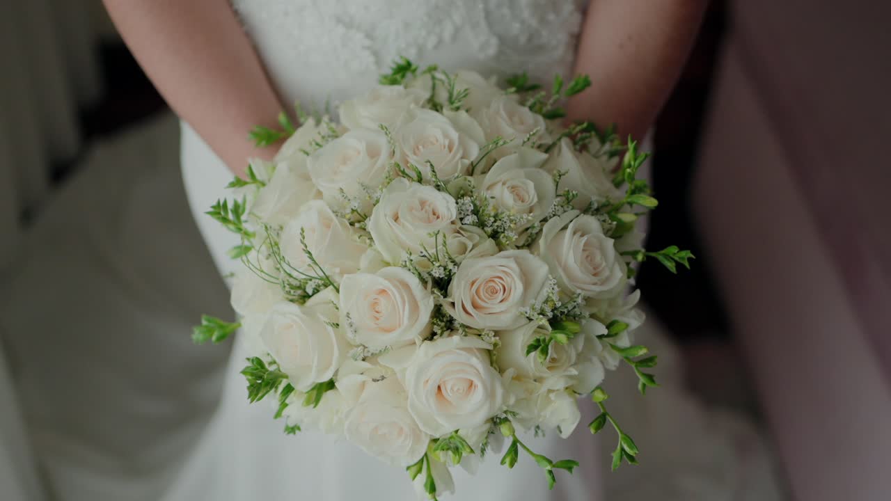 primo piano di una sposa che tiene un bouquet di rose bianche