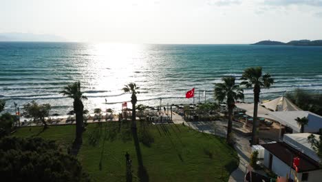 Luftlandschaft-Der-Küste-Von-Kusadasi-Bei-Sonnenuntergang,-Türkische-Flagge-Im-Hintergrund