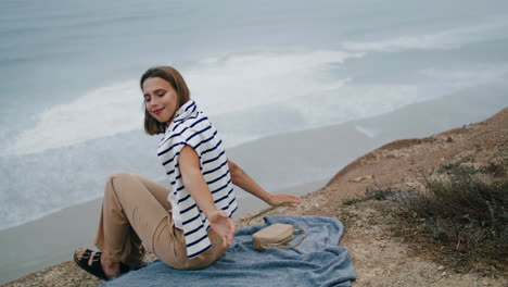 serene woman resting ocean cliff edge vertical. smiling tourist looking camera