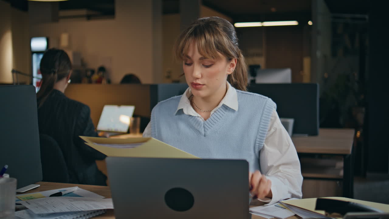 Impiegata che esamina documenti sulla scrivania dell'ufficio aziendale, primo piano. Donna che si occupa di scartoffie