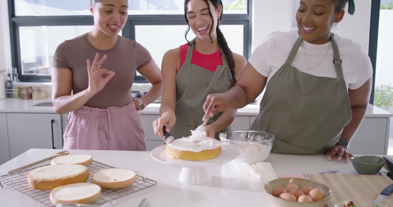Amigas diversas reagindo ao telefone com ring light, confeitando bolo na ilha da cozinha e filmando a receita.