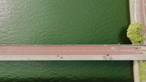 aerial top down of bridge over the ocean water with traffic of cars and pedestrian reaching the main city centre downtown during rush hours