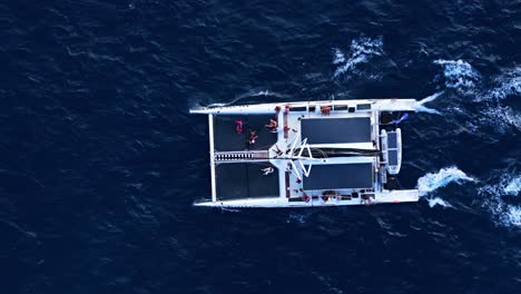 aerial top down tracking follows catamaran mast in open ocean deep blue water