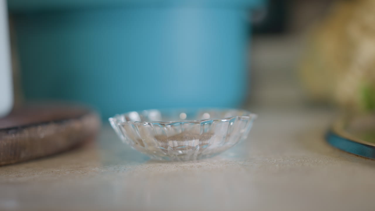 Scena calma con piatto di vetro. Ambiente sereno della cucina di casa con un piatto in attesa degli ingredienti. Ambiente cucina elegante e tranquillo con contenitore di vetro vuoto sotto una morbida illuminazione naturale