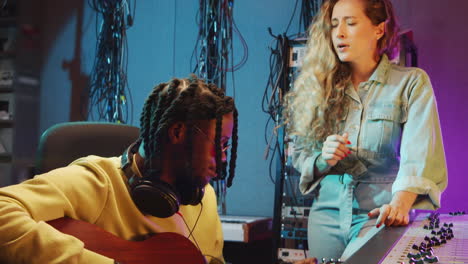 hombre y mujer cantando a la guitarra en el estudio de grabación