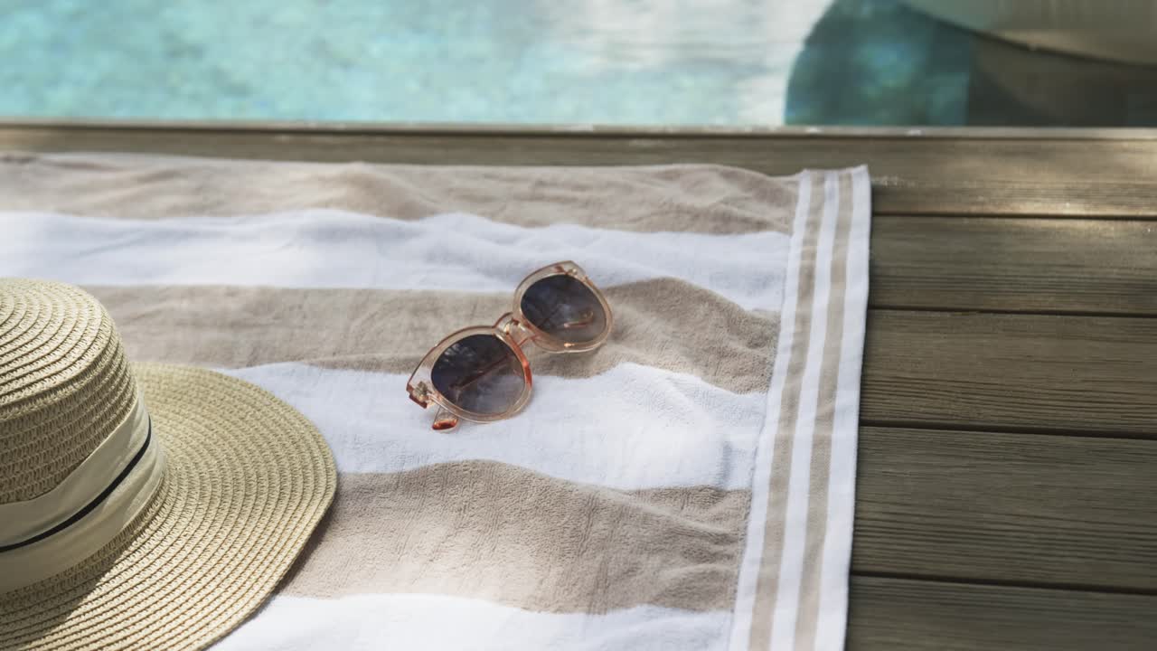 Camera panning and zooming is bringing clear shades closer on striped towel to show poolside calm