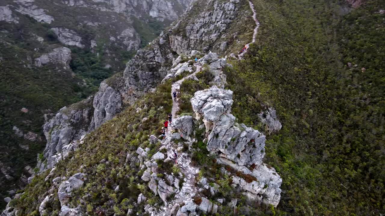 Hikers on a mountain ridge with huge cliffs and steep drop offs