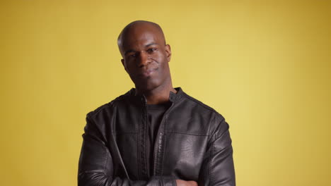 head and shoulders studio portrait of smiling mature man against yellow background 1