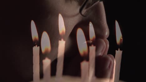 Composite-video-of-burning-candles-against-close-up-of-a-caucasian-woman-praying