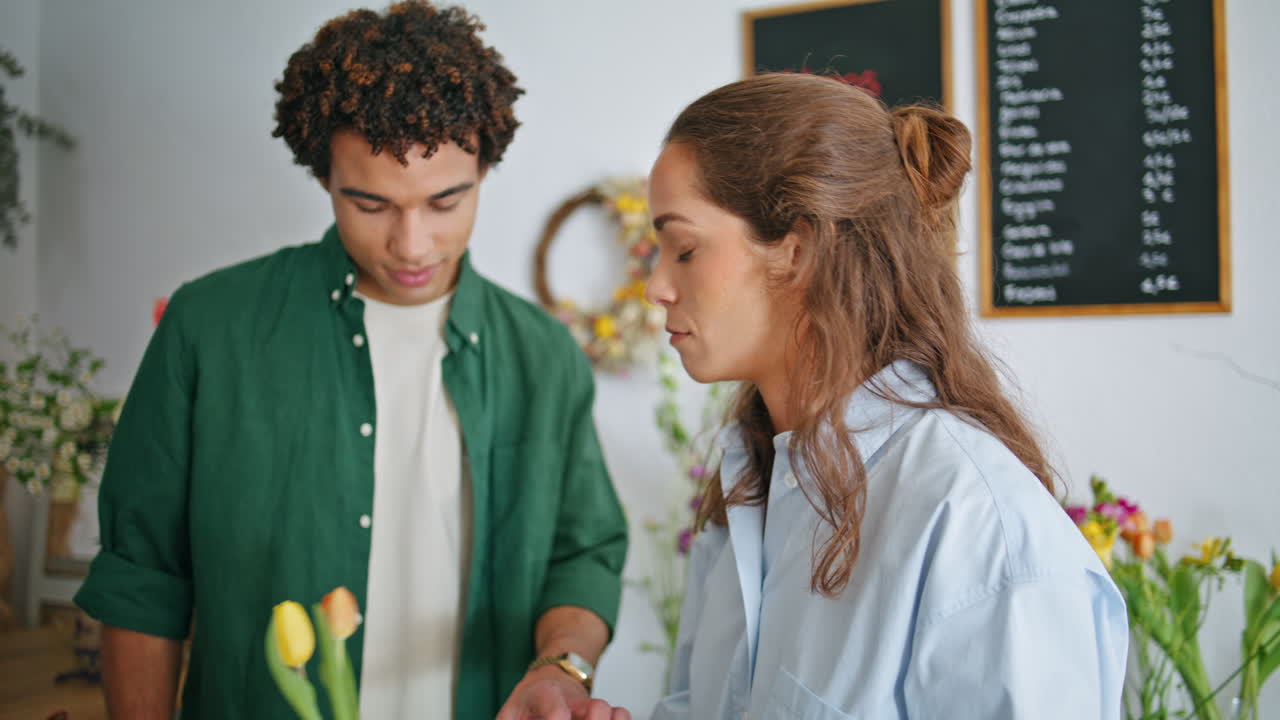 florista milenario ayuda al cliente a comprar composiciones de flores en una tienda de flores creativa