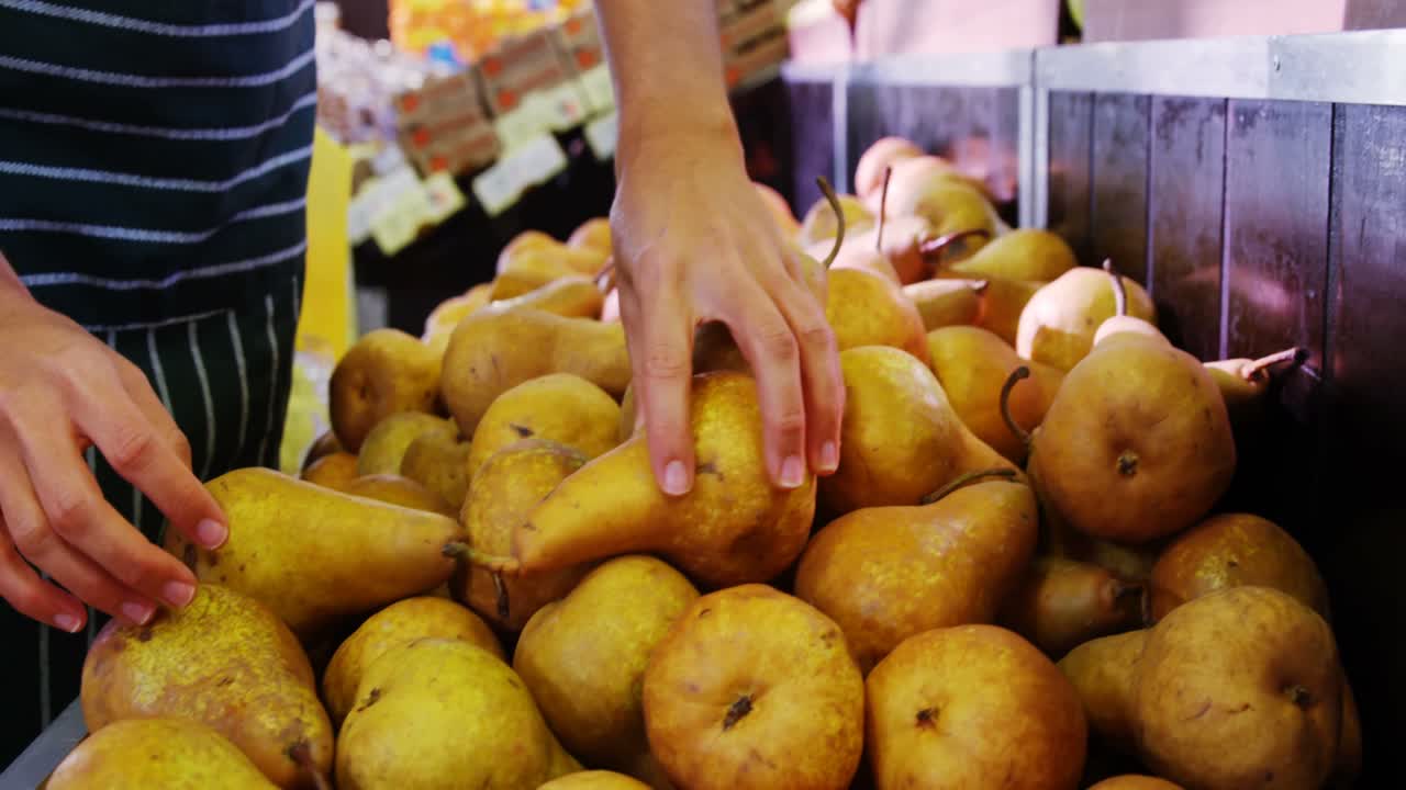 personal femenino que arregla las peras en la sección orgánica