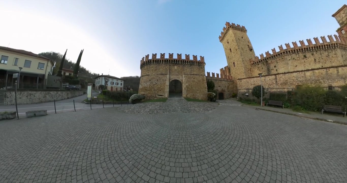 La telecamera scivola attraverso il portone in pietra e lungo le mura interne della Rocca Viscontea con un movimento a 360 gradi.