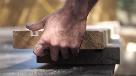 worker's hand picking up wood planks with grooves at the workshop