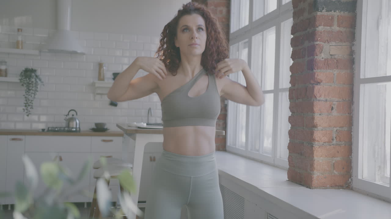 Donna che fa stretching alle spalle in cucina