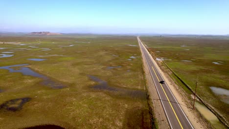 car-on-lonely-highway-aerial-near-merced-california