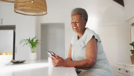 Happy-senior-african-american-woman-using-smartphone-at-home