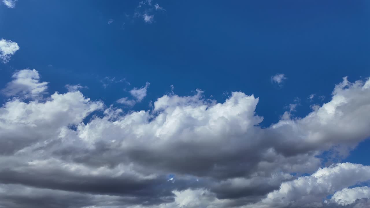 A timelapse of a ever-changing cloudscape, low angle shot, with white fluffy clouds moving in a deep blue sky