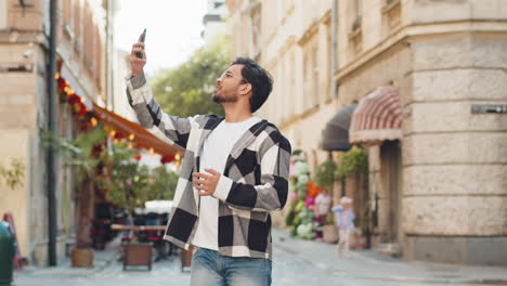 young male tourist trying to catch communication signal and internet on smartphone in city street