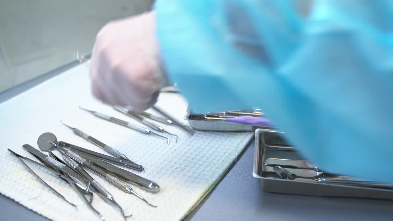 Hands of medic nurse arranges metal tools. Medical worker placing instruments into little metal boxes. Close up.