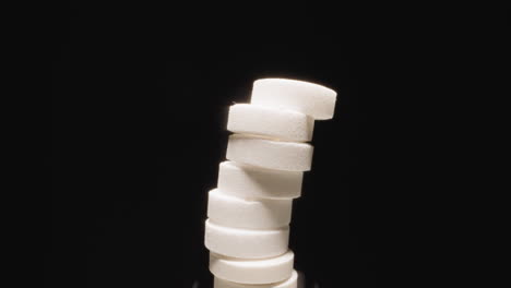 curved stack of white round pills shaking ready to collapse