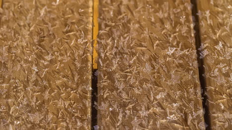 un primerísimo plano de copos de nieve y hielo derritiéndose sobre placas de madera térmica