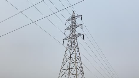 Network-of-high-tension-electricity-pylon-power-lines-crossing-above-hazy,-misty-Bangladesh-sunrise-skyline