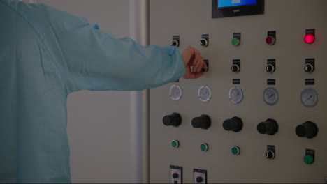 trabajador, vestido con un uniforme azul, activa la máquina en la fábrica