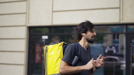 Un-Tipo-Barbudo-Con-Una-Mochila-De-Reparto-Está-Bromeando,-Cámara-Lenta