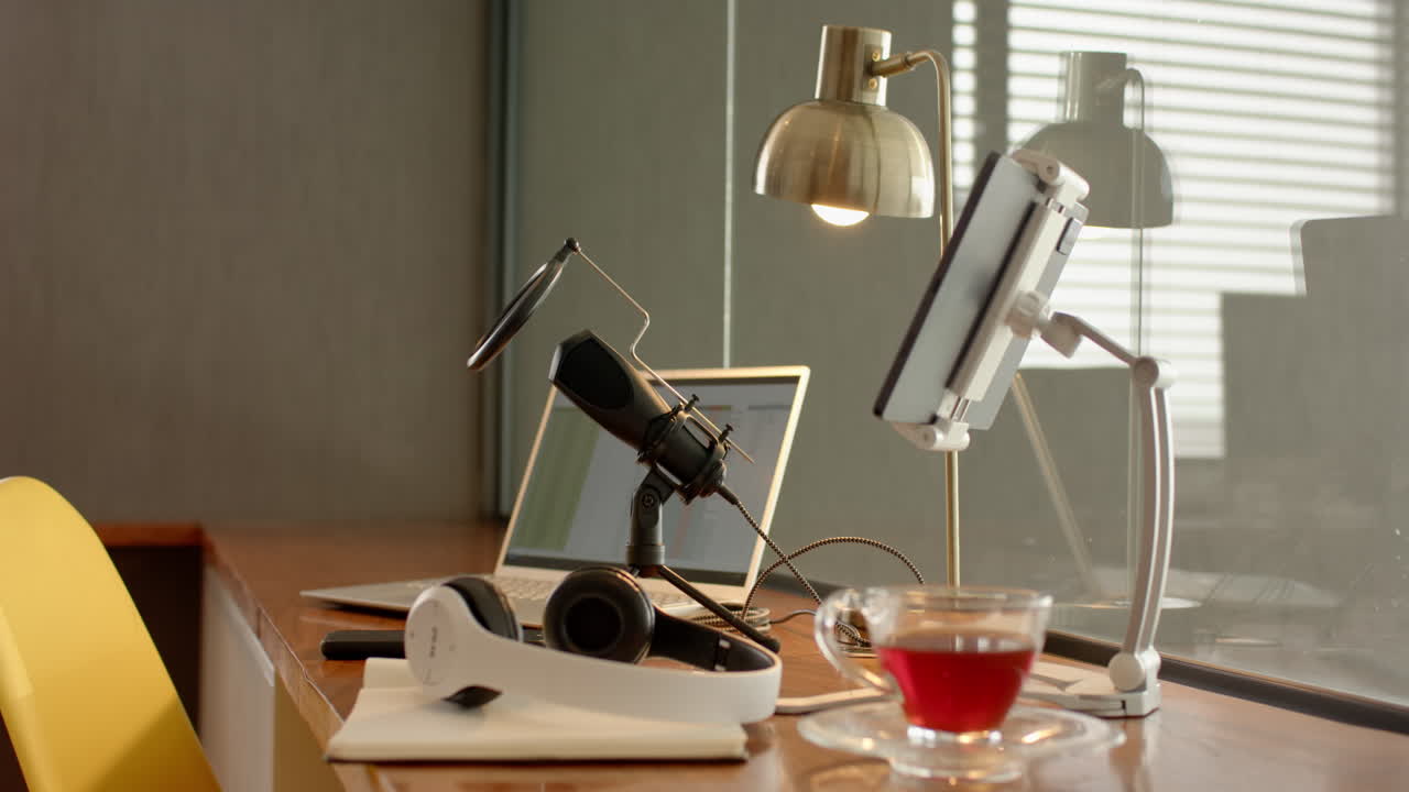 Recording podcast, microphone and headphones on desk with laptop and tablet, at home