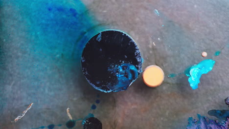 Macro view of prominent dark blue circular shaped ink with other small different colored inks in liquid