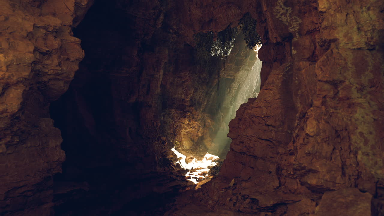Luce solare che filtra attraverso l'apertura di una grotta vicino a una costa rocciosa all'alba