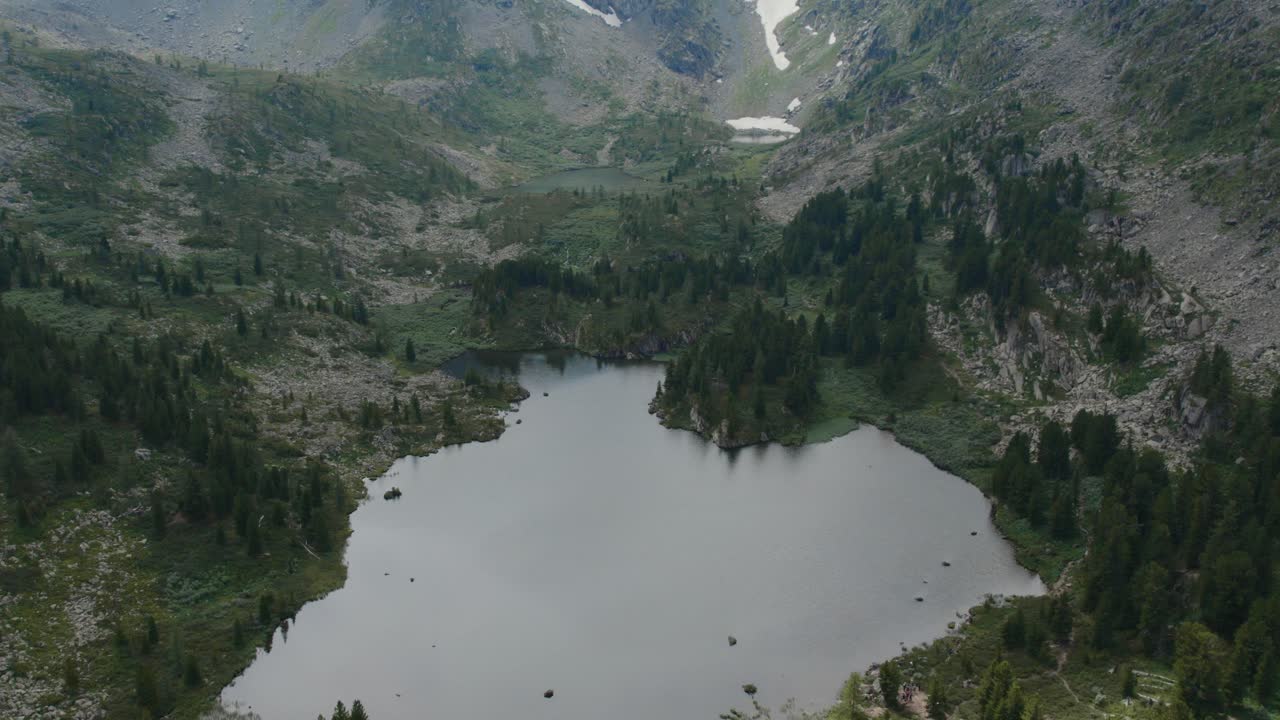 Droneoptagelser over Karakol-søerne omgivet af klippefyldte skråninger, taigaskov og pletter af sne i Altai-bjergene, Sibirien, Rusland, fjerntliggende sommerlandskab.