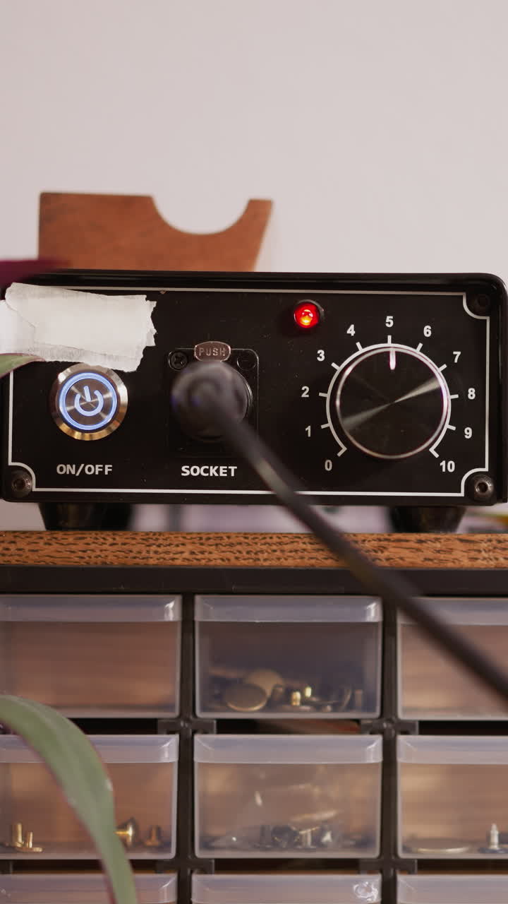 Man turns on and tunes electrical leather edger to work in handicraft workshop closeup. Master uses creasing machine in studio. Craftsman equipment