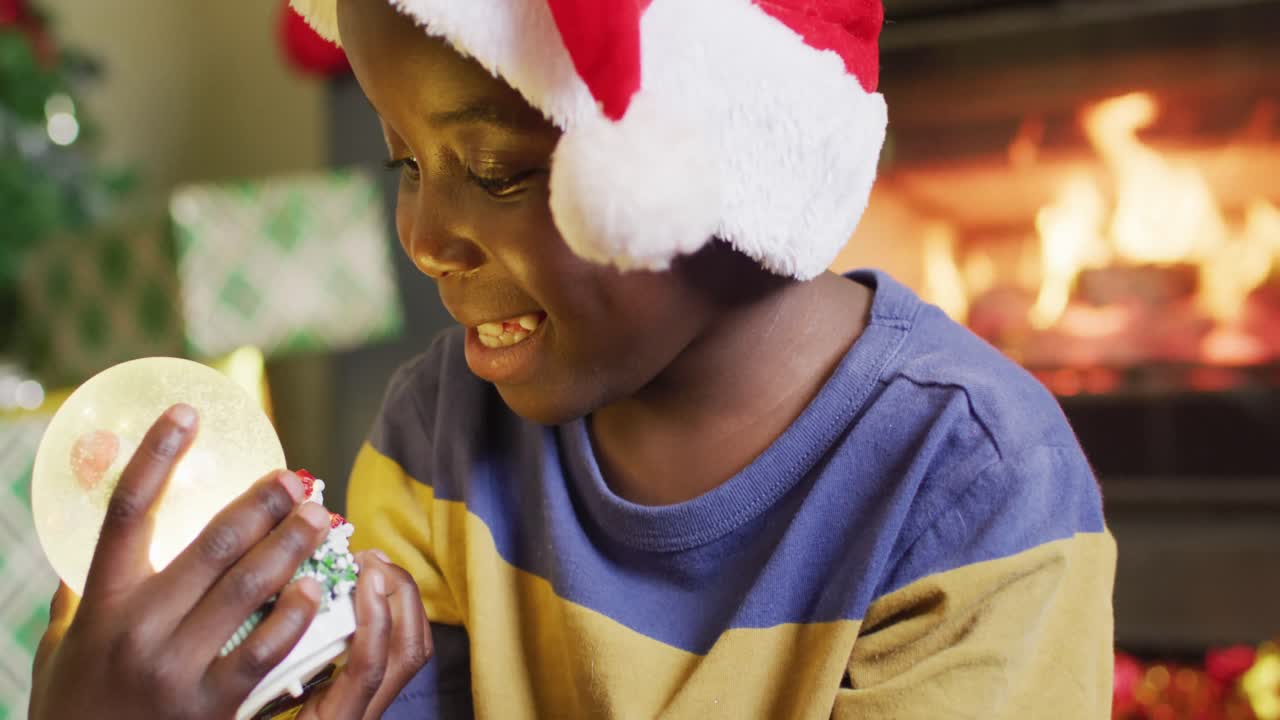 un niño afroamericano feliz jugando con un globo de nieve.